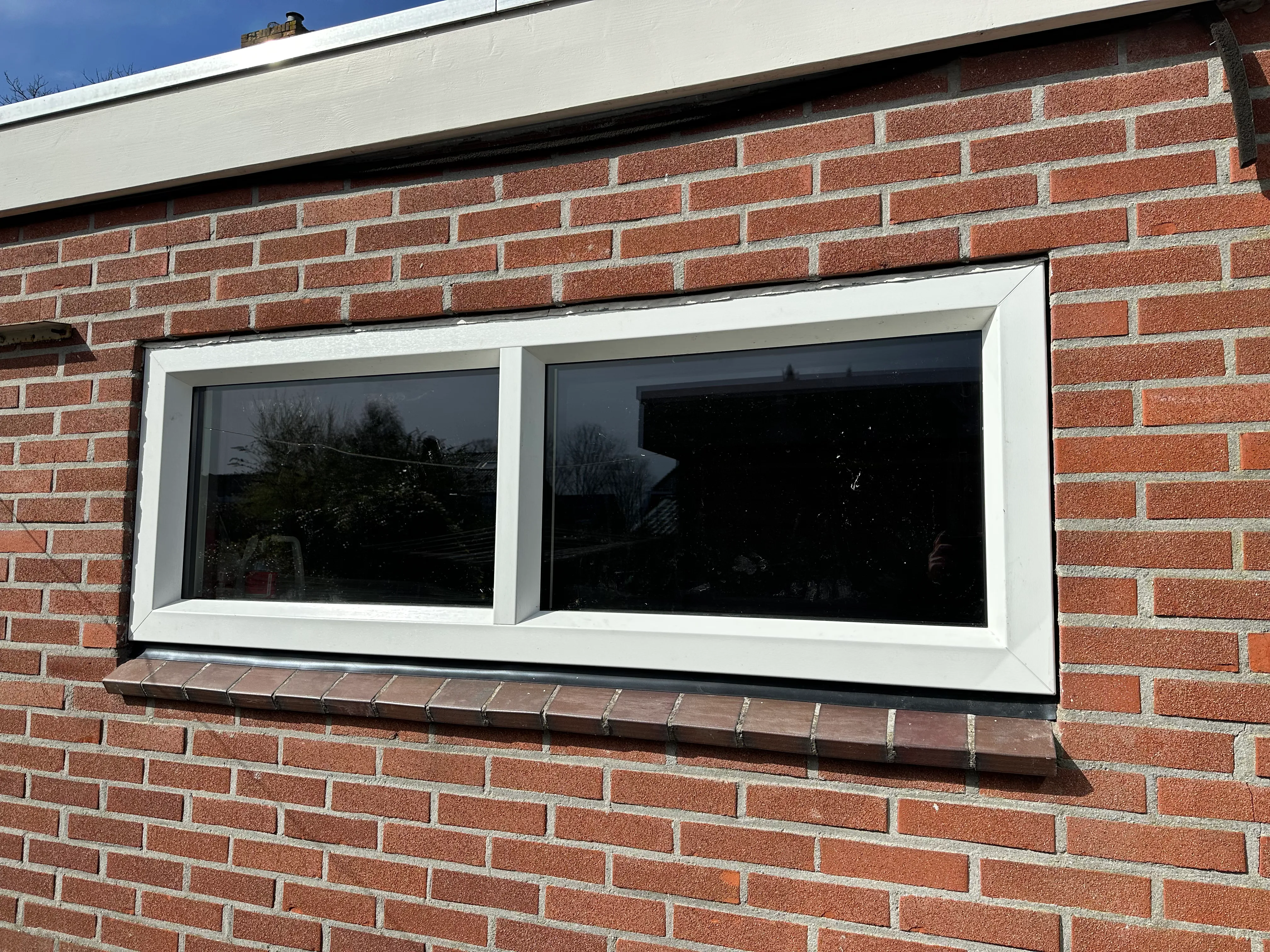 Breed liggend kunststof kozijn in rode baksteengevel