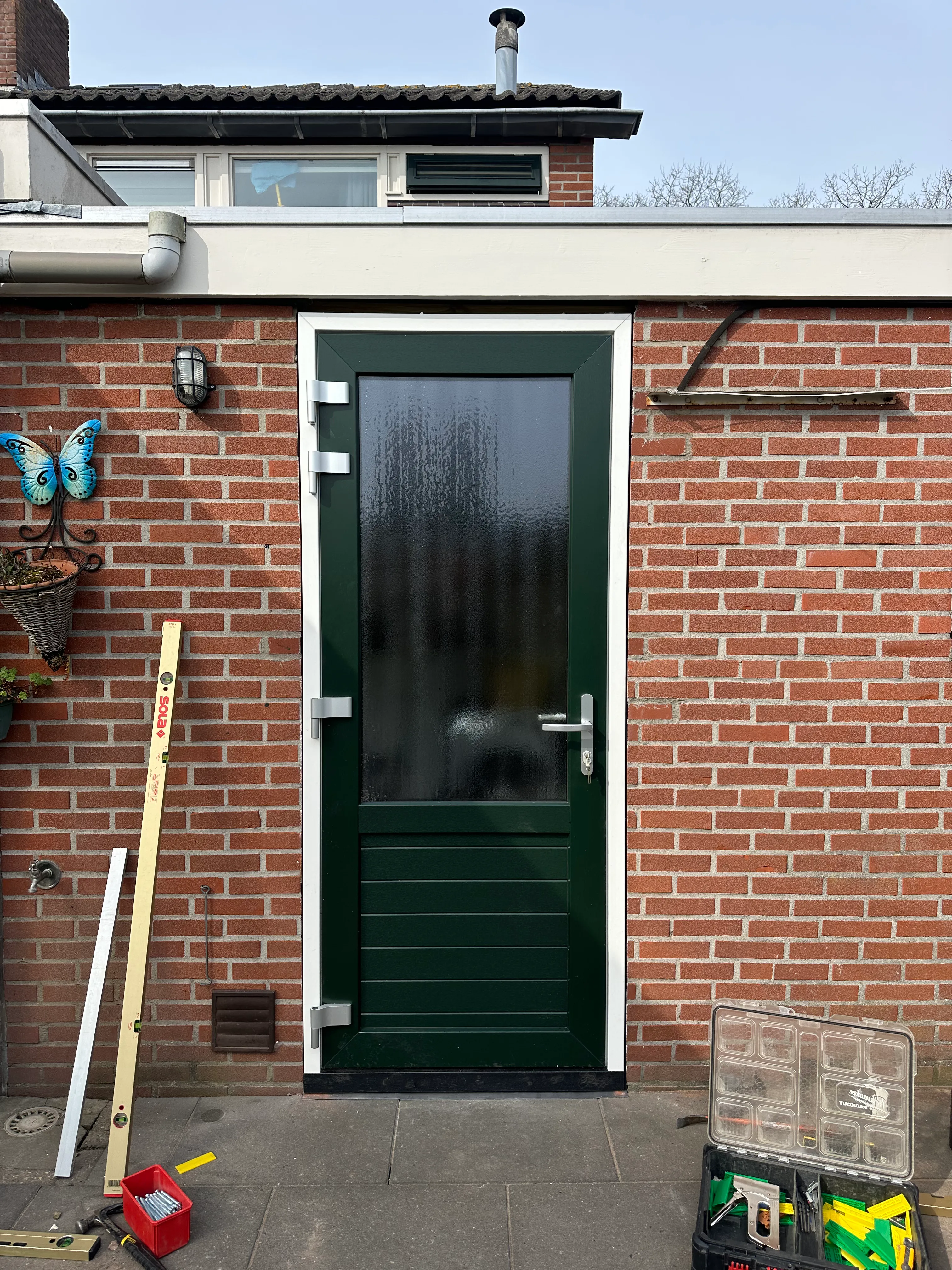 Nieuwe donkergroene kunststof achterdeur in rode baksteengevel