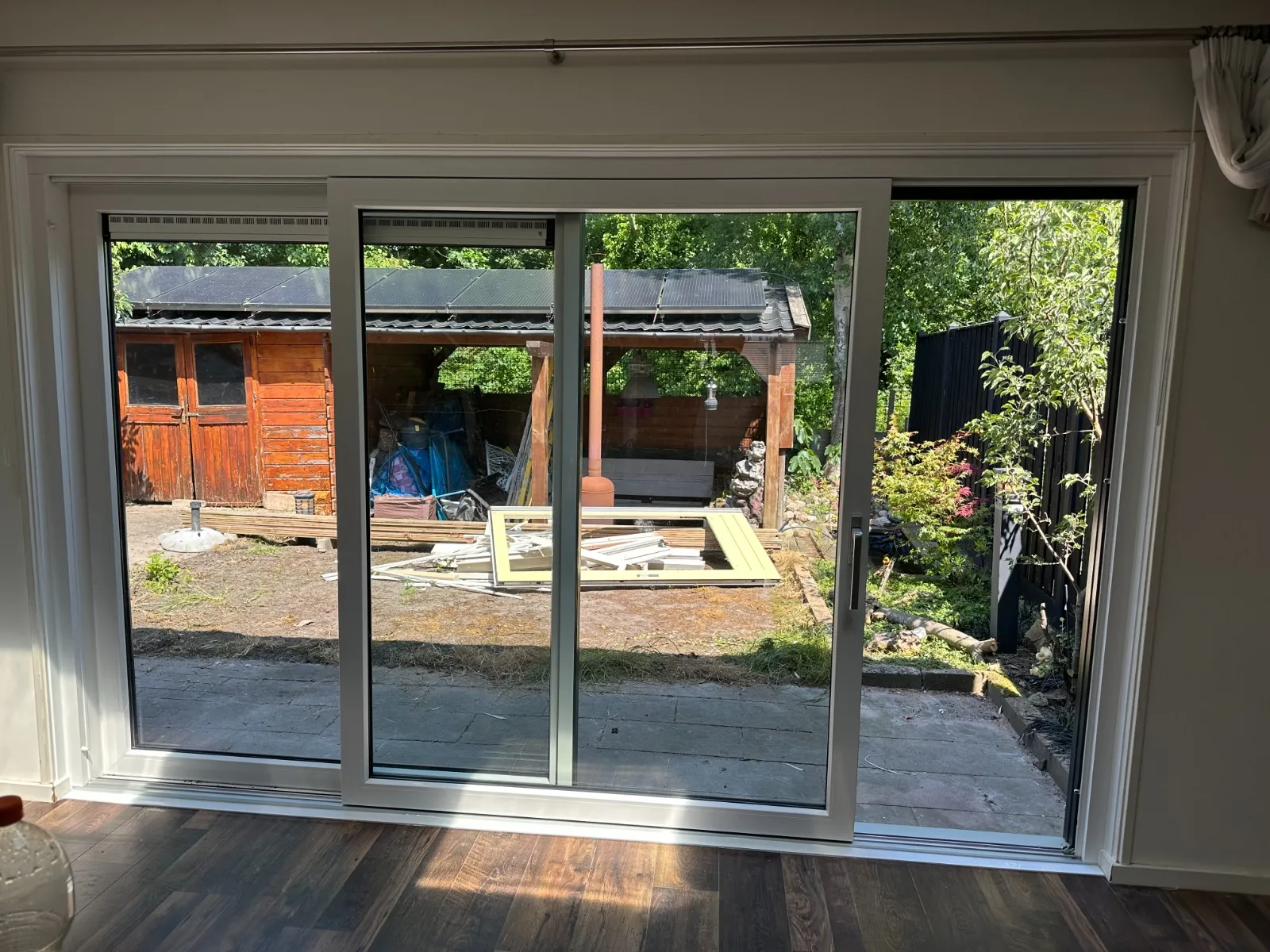 Binnenaanzicht van brede kunststof schuifpui met uitzicht op de tuin