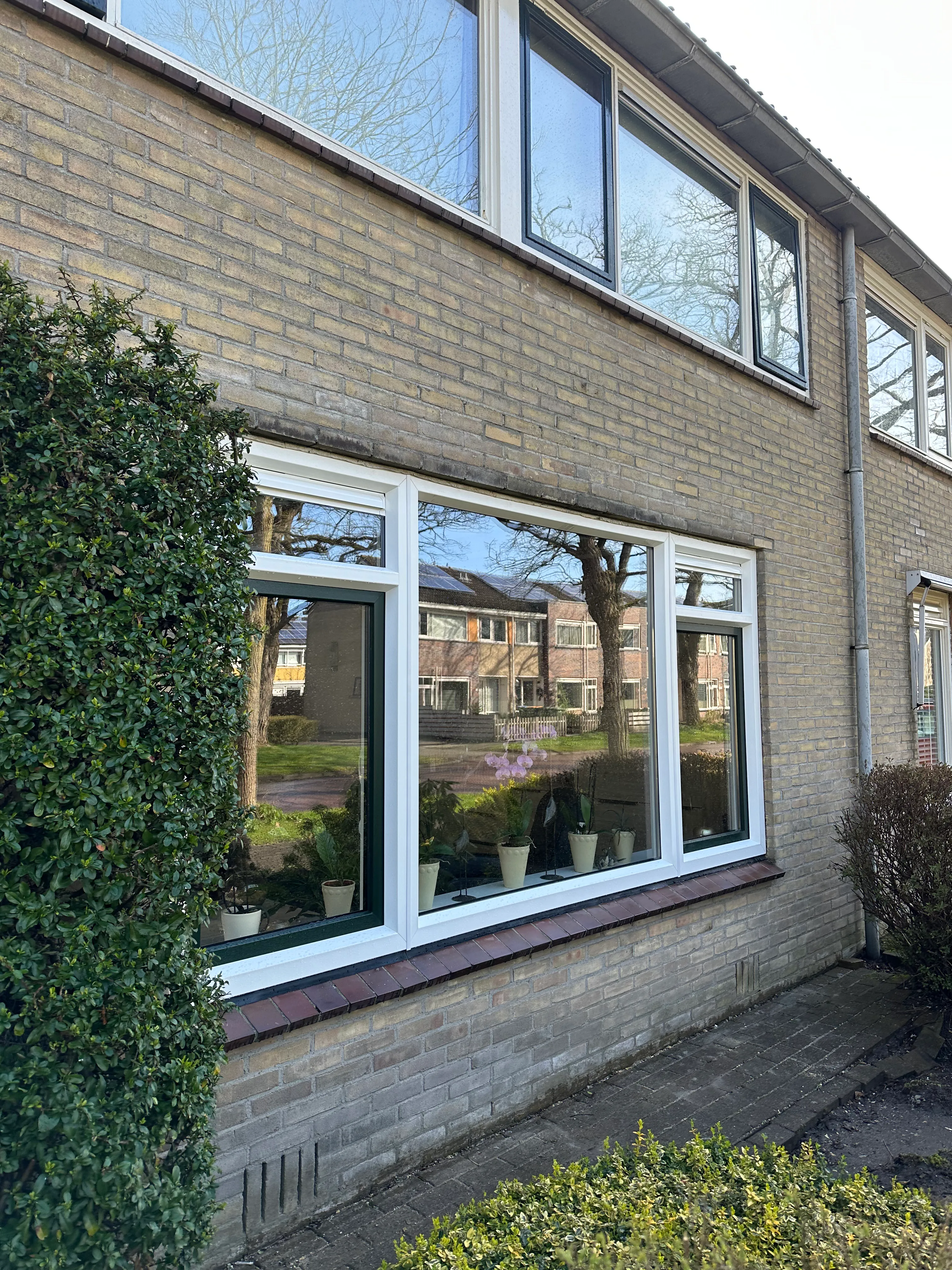 Gevel met nieuwe brede kunststof kozijnpartij en veel glas